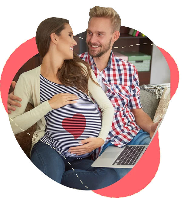 smiling_pregnant woman, husband hugging while women is holding her bump. researching on laptop
